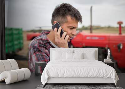 Male agronomist standing in harvested field talking on phone Wall mural