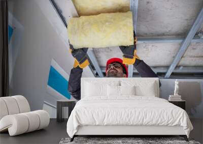 Male worker insulating attic with glass wool. Wall mural