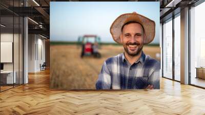 Portrait of farmer with straw hat in front of tractor Wall mural