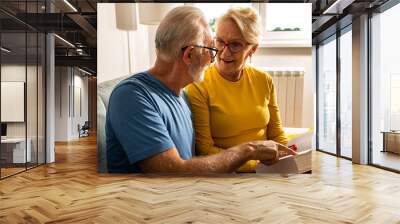 Senior couple reading book at home Wall mural