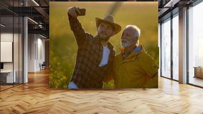 Two farmers taking selfie in field at sunset Wall mural