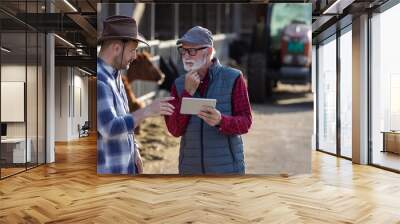 Two farmers using tablet on cow farm Wall mural