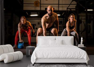 Fit group people in exercise gear standing in a row holding dumbbells during an exercise class at the gym Wall mural