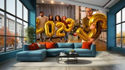 Group of young beautiful people in casual clothing carrying gold colored numbers and smiling. Goodbye 2022. Wall mural