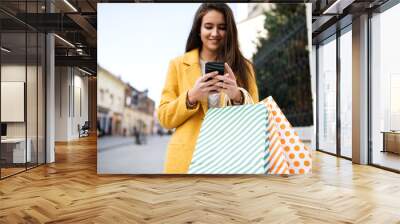 Woman in a yellow coat using mobile Wall mural