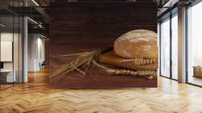 Freshly baked traditional bread with wheat on wooden background. Wall mural