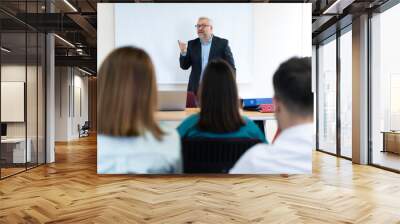 A group of people are sitting at a table with laptops and a projector. They are likely discussing a project or presentation Wall mural