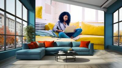 African American woman using laptop at home Wall mural