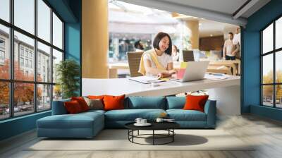 Asian woman working on laptop in office Wall mural