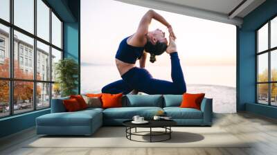 Caucasian flexible female care about body stretching and harmony during yoga meditation exercising asana at stone, woman doing Pigeon pose concentrated on training muscles and pilates practice Wall mural