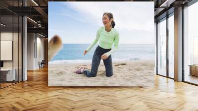 Cheerful 40 years old woman playing with dog on waterfront Wall mural