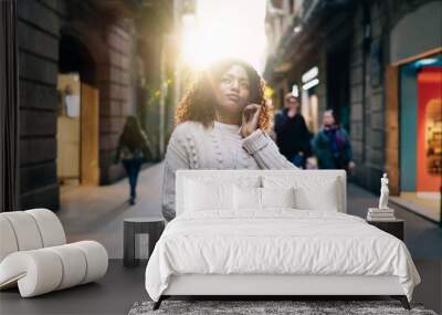 Cheerful black woman listening to music on street Wall mural