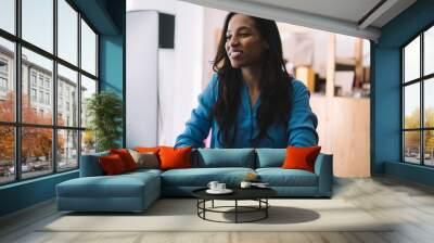 Cheerful black woman typing looking at monitor at table Wall mural