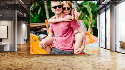 Cheerful couple spending time together near car in exotic place Wall mural