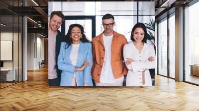 Cheerful male and female colleagues satisfied with friendly teamwork brainstorming in office interior, successful multiracial employees smiling and laughing during partnership in workspace Wall mural