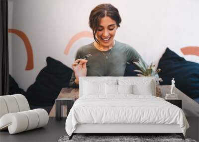 Cheerful young woman enjoying bruschetta with salmon while sitting in cozy restaurant Wall mural