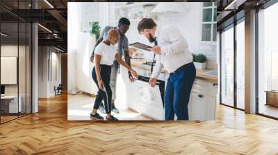 Confident estate agent showing kitchen to African American thoughtful couple Wall mural