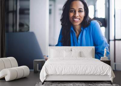 Confident ethnic businesswoman using laptop at work Wall mural