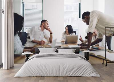 Coworkers smiling and talking during business meeting Wall mural