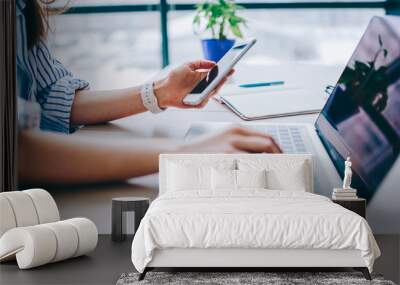 Cropped image of female holding smartphone getting message with confirmation making transaction on laptop computer,woman using mobile phone app for synchronizing data with netbook via bluetooth. Wall mural