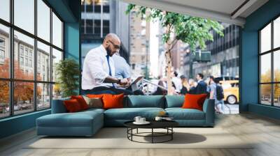 Focused black businessman typing message on city street Wall mural