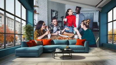 Glad friends smiling and drinking coffee with pizza at home Wall mural