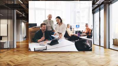 Group of diverse colleagues discussing project together at workplace Wall mural