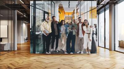 Group of diverse colleagues smiling and standing together in office corridor Wall mural