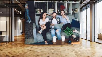 Group of young hipsters laughing and sitting on couch Wall mural