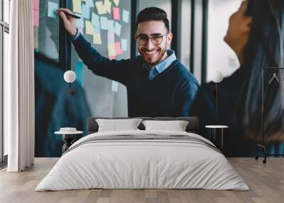 half length portrait of happy young man smiling at camera while writing down notes on paper colorful Wall mural