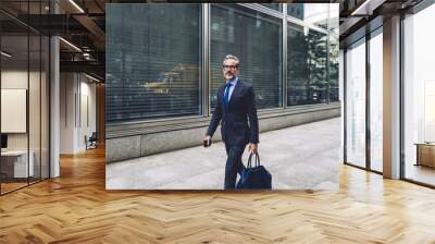 Handsome mature man striding down street Wall mural