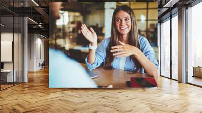 happy successful hipster girl explaining information to male friend sitting in front, positive man a Wall mural