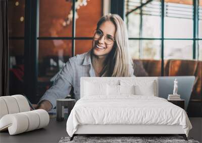 Happy young woman with papers and laptop Wall mural