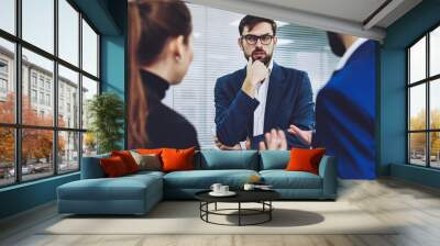 Male trader in formal wear puzzled on ideas for productive strategy of development business company with professional colleagues, executive managers cooperating on startup project in office Wall mural