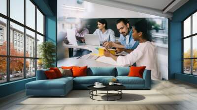 Multiethnic workgroup of young employees developing strategy at meeting in office Wall mural