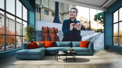 Pleased adult modern female browsing smartphone on street stairs Wall mural