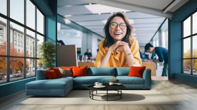 Portrait of excited hipster student in classic glasses for vision protection feeling excited and laughing during free time in university classroom, happy smiling Chinese woman e learning indoors Wall mural