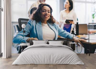 Portrait of successful female entrepreneur 30s smiling at camera during collaboration day in office interior, happy African American corporate director in smart casual apparel posing in workspace Wall mural