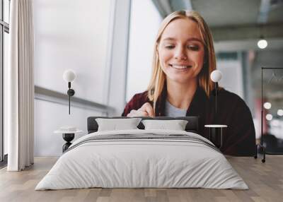 Positive blonde woman fill in information in questionnaire making application for hire on vacancy, smiling female students satisfied with know answers for test completing writing with pen indoors Wall mural