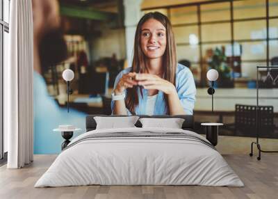 positive smiling woman with brunette hair sitting at wooden table and talking with male friend in fr Wall mural