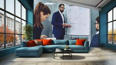 Professional economist standing near white board with graphic and explaining information for project, successful business people collaborating togetherness and solving problems together in company Wall mural