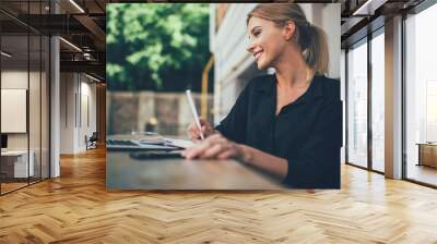 Satisfied female remote worker with laptop at outdoors cafe veranda Wall mural