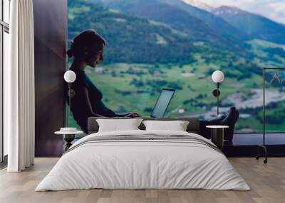 Skilled female digital nomad working remotely creating trip guide to high mountains for share to followers in social networks connected to 4g internet, skilled freelancer typing text on laptop Wall mural