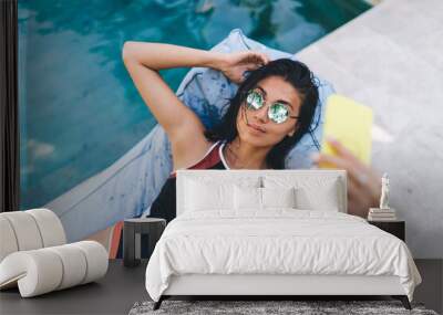 Slim woman taking selfie lying on beanbag lounge Wall mural