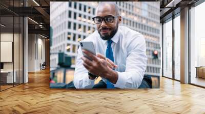 Smiling formal businessman browsing mobile sitting on street stairs Wall mural