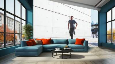 Sporty guy jogging in urban street Wall mural