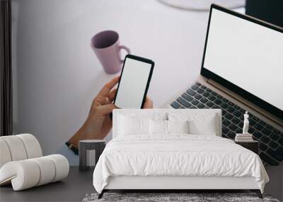 Student sitting at table with laptop and using smartphone Wall mural