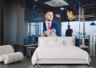 Successful male and female proud ceo discussing business strategy for financial project analyzing paper report in office workspace, formally dressed colleagues talking about exchange productivity Wall mural