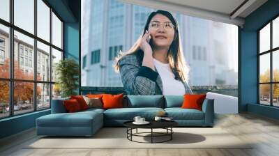 Successful woman entrepreneur calling to colleague for communicating about startup project while working remotely on it via laptop computer, young female using roaming connection on cellular phone Wall mural