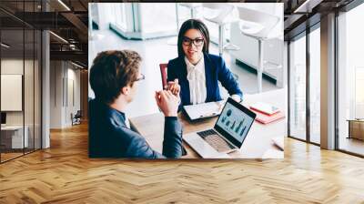 Two female colleagues have important meeting with male finance director of company discussing details of good trade indoors, group of economists sitting at desktop with laptop talking about statistics Wall mural